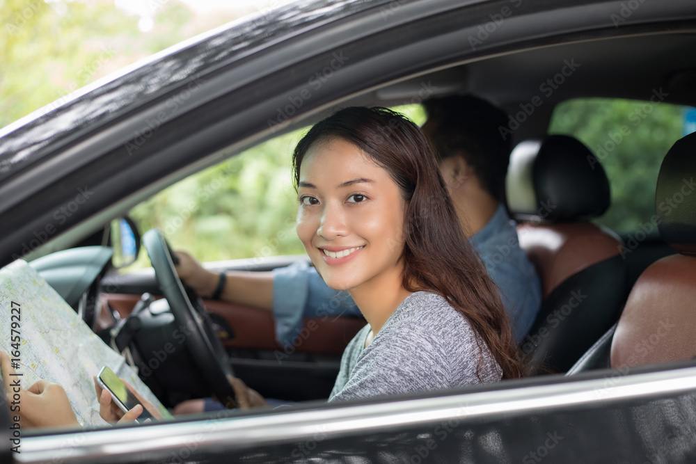 Asian woman using smartphone and map and men driving car on road trip and Happy young couple with a map in the car. Asian woman using smartphone and map and men driving car on road trip and Happy young couple with a map in the car.