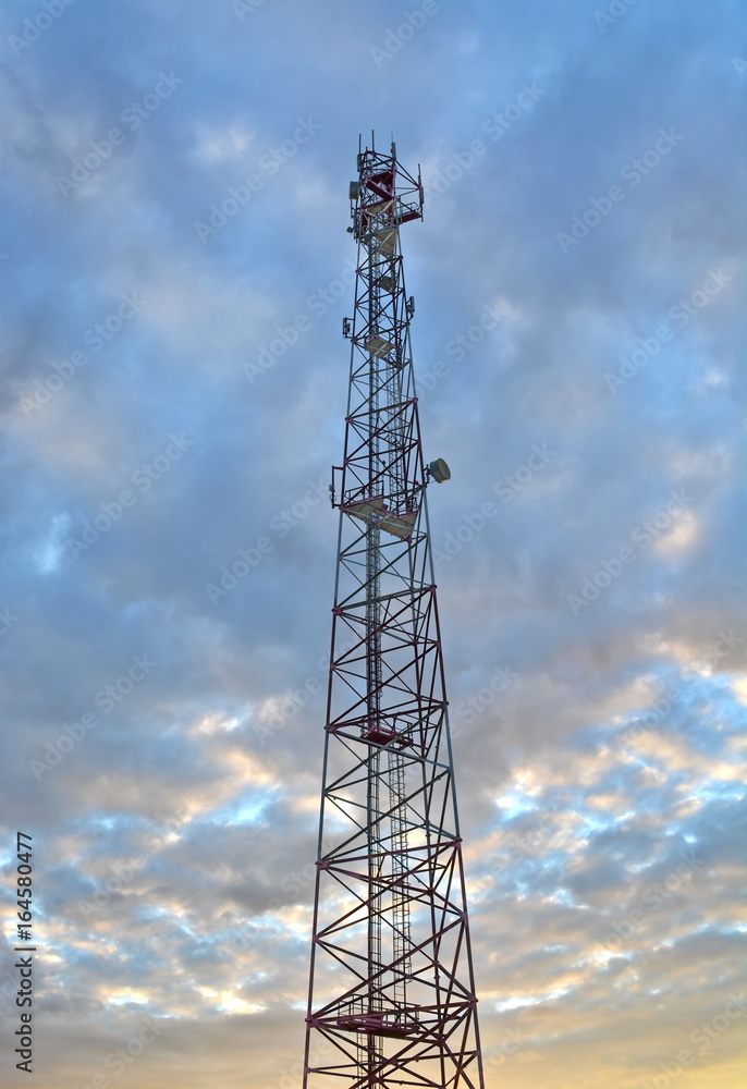 communications tower cell mobile with equipment with sunset ray evening sky background