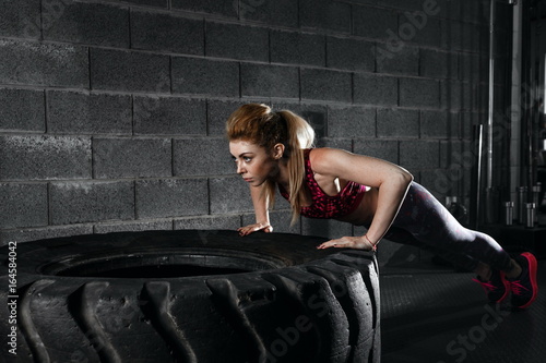 Sportswoman. Fit sporty woman doing push ups on tire strength po © ProstoSvet