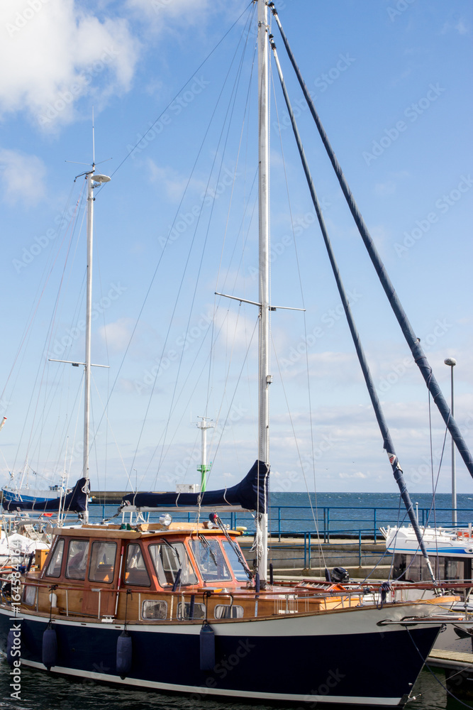 Obraz premium Wooden blue yacht stands near the pier