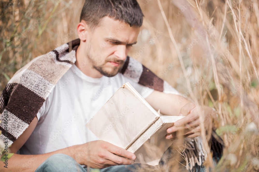 Fototapeta premium a young man on the field reading a book