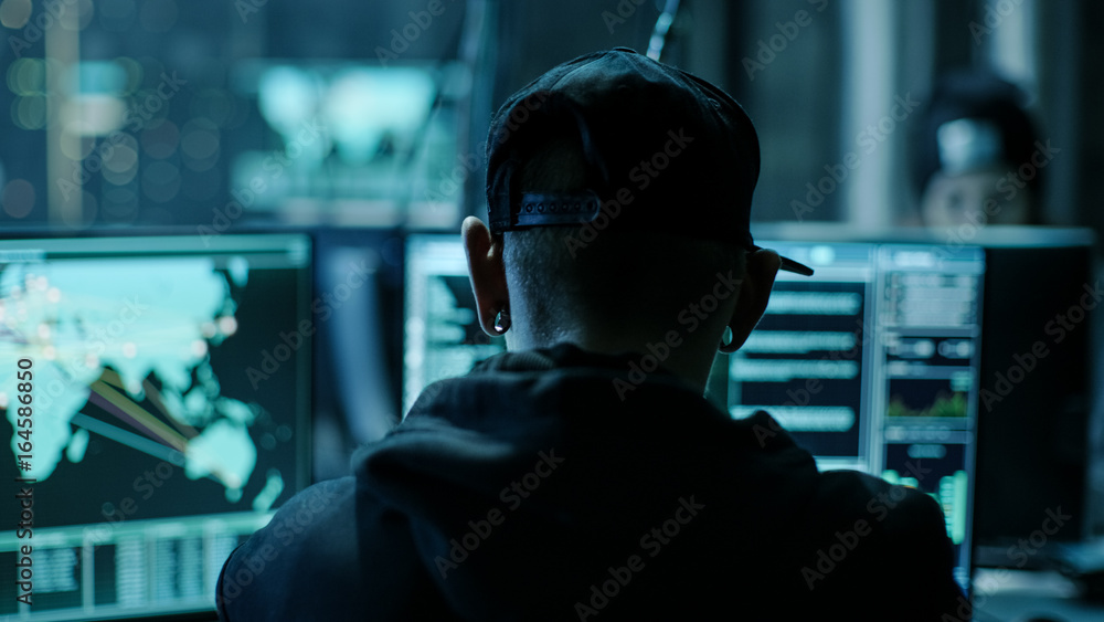 Close-up Frame from the Back of Working Hacker Organizing Advanced Virus Attack on Corporate Servers. Place is Dark and Has Multiple displays. Close-up Frame from the Back of Working Hacker Organizing Advanced Virus Attack on Corporate Servers. Place is Dark and Has Multiple displays.