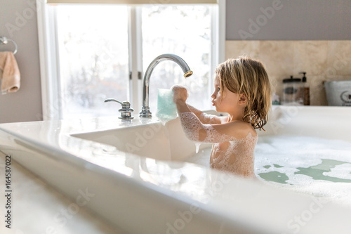 Girl playing with water in bubble bath  photo