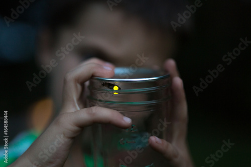 Child holding jar with firefly inside, close-up