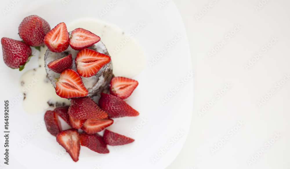 Delicious homemade chocolate cake with fresh red strawberries and cream sauce on white plate. Delicious homemade chocolate cake with fresh red strawberries and cream sauce on white plate.