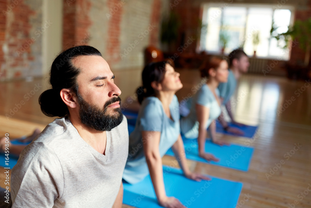 group of people doing yoga cobra pose at studio group of people doing yoga cobra pose at studio