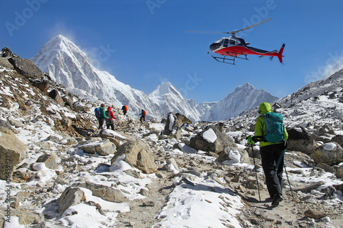 Goup of climbers in the Himalayas, view on peaks Lingtren, Pumori and Khumbutse. Rescue helicopter in action, Nepal photo