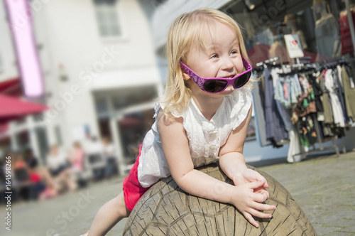 Pretty little girl with curly blond hair playing outdoors on a sunny summer day