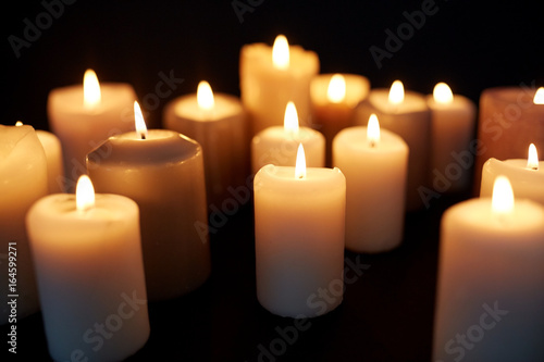 candles burning in darkness over black background