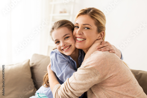 happy smiling family hugging on sofa at home