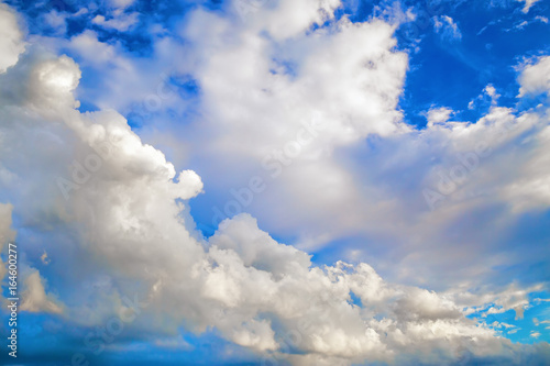 White cumulus clouds against a bright blue sky.
