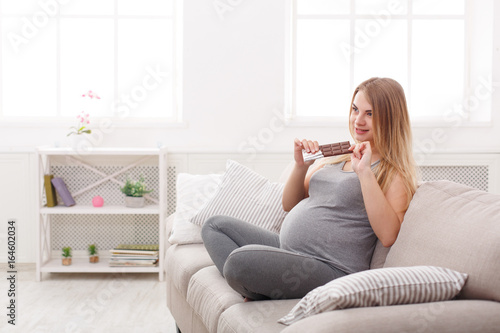 Pregnant woman enjoying of eating chocolate bar