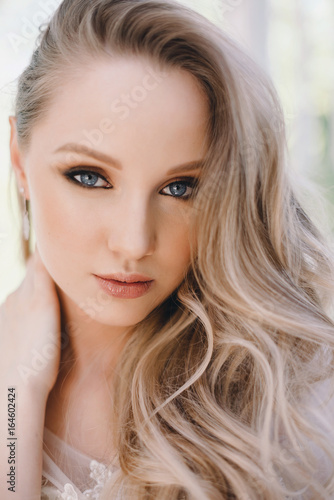 Studio Portrait of Beautiful Model with Volume Shiny Wavy Blond Hair. Fashion Make Up and Curly Ombre Hair. Close up