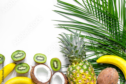 Concept of summer tropical fruits. Pineapple, kiwi, banana, coconut on white background top view copyspace