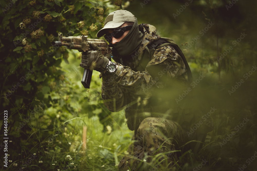 Military in camouflage among trees