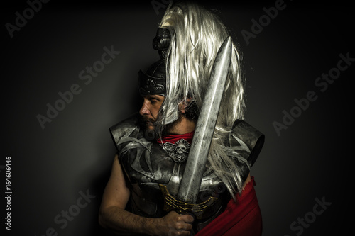 Roman centurion with armor and helmet with white chalk, steel sword and long red cape