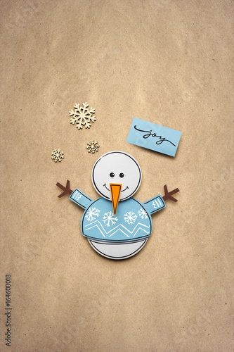Merry christmas / Creative photo of a snowman made of paper on brown background.