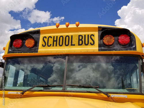 yellow school bus with summer cloud reflection in windshield