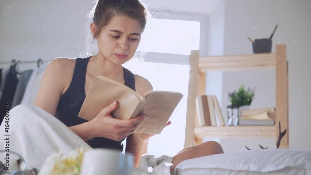Young Caucasian lady reading book in bed in slowmotion. Concept of morning Young Caucasian lady reading book in bed in slowmotion. Concept of morning