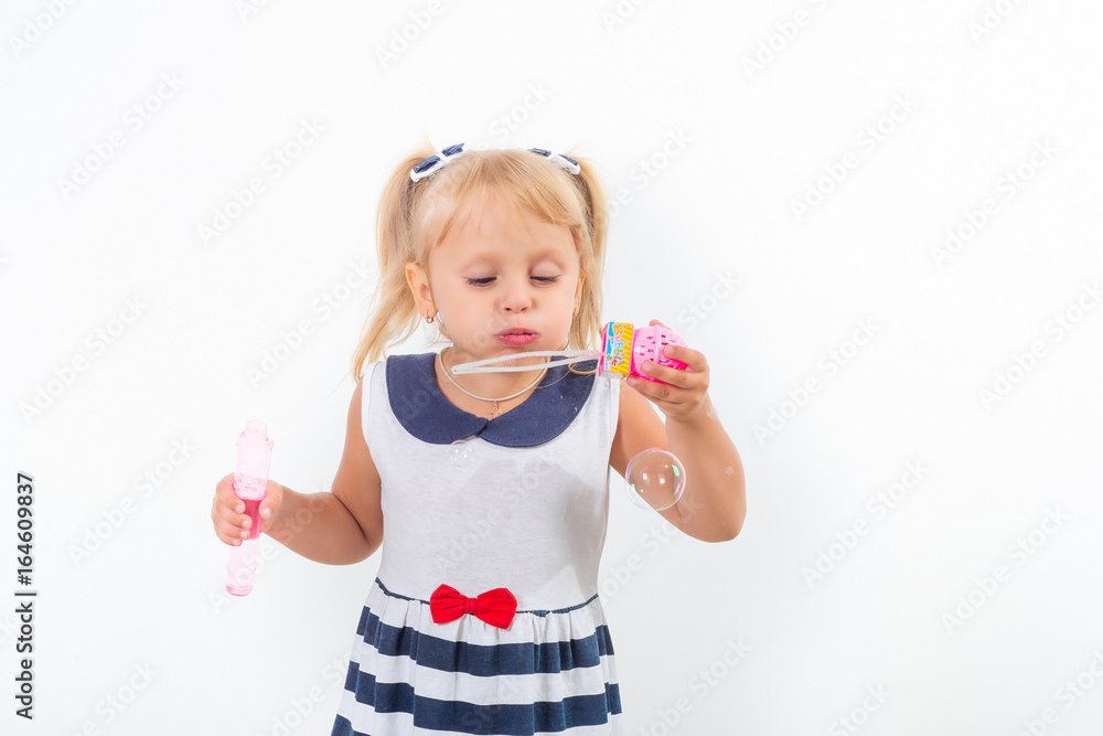Little girl is playing with soap bubbles. Happy childhood. Joyful emotions.