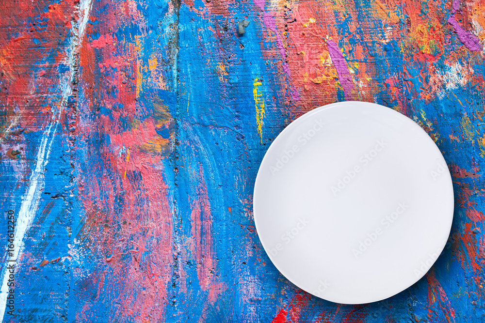 Top view of empty white plate put on colorful table with space for copy.