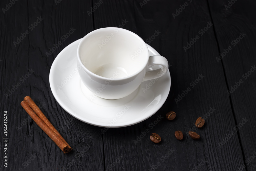 Empty coffee cup with a cinnamon stick on a black background Empty coffee cup with a cinnamon stick on a black background