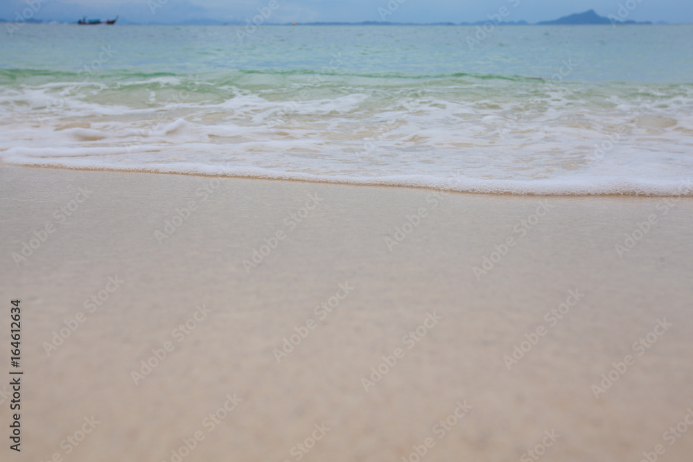 Abstract blurry background of sandy beach with soft waves.