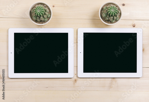 Top view of white tablet isolated black screen with cactus flowers on wood table background for advertising display or mockup design