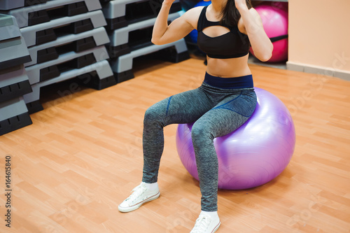 Pretty sexual straight fitness woman with musculat body lying on big ball in sport hall training indoor, horizontal picture