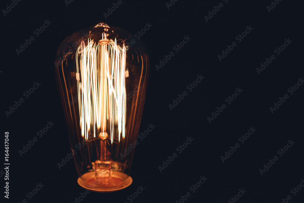 Close-up of glowing retro light bulb on a black background. Copy space.