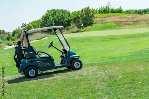 Close up of a golf cart with sticks, a golf course, golf balls and green grass. Concept rest and sport.