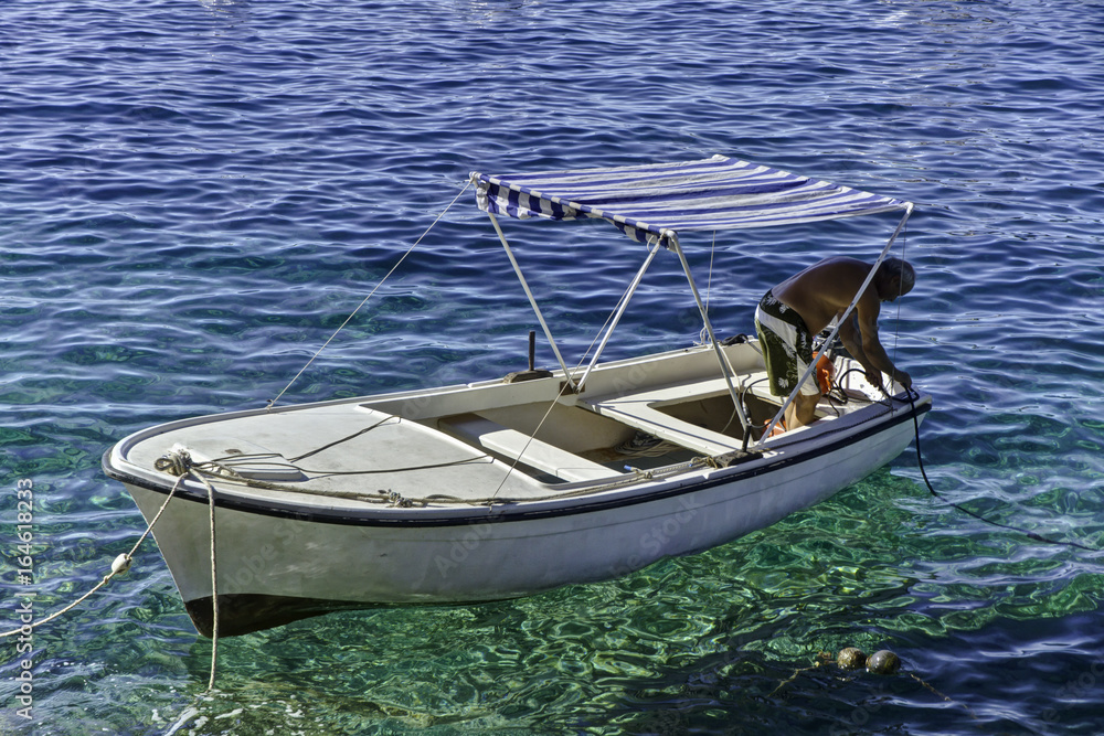 Man preparing small boat in the calm water of Hvar, Croatia Man preparing small boat in the calm water of Hvar, Croatia