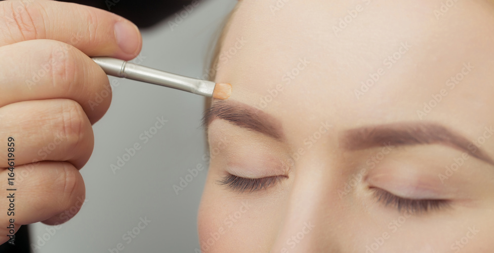 Woman with closed eyes getting makeup on face