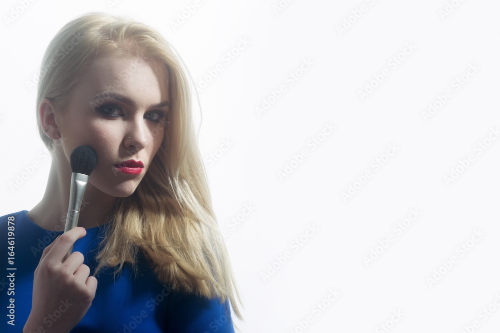 Girl with red lips applying makeup on face with brush Girl with red lips applying makeup on face with brush