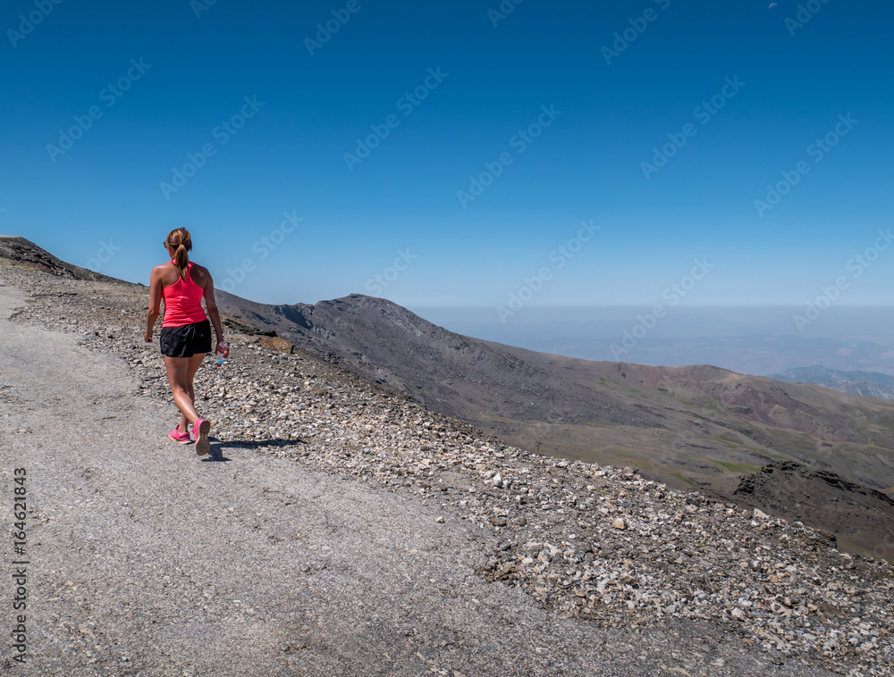 Young woman walking up to the top of the Sierra Nevada Mountain peak