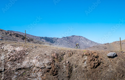 People mountain biking down race on track trail in the Sierra Nevada Mountains in Spain on a sunny day.