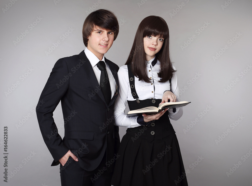 Happy teenagers in school uniform portrait. Handsome boy and beautiful brunette girl posing isolated on studio background. Happy teenagers in school uniform portrait. Handsome boy and beautiful brunette girl posing isolated on studio background.