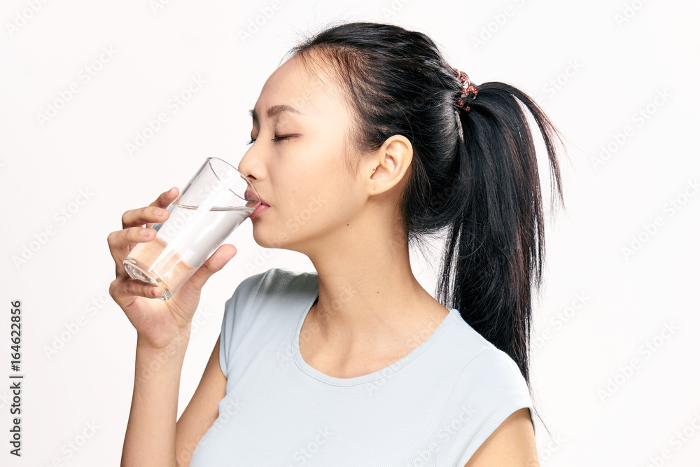 Young beautiful woman on white isolated background drinks water, asian Young beautiful woman on white isolated background drinks water, asian