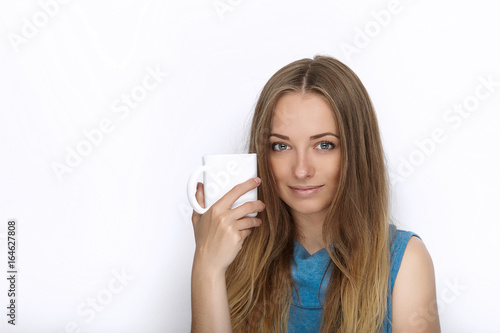 Headshot of young adorable playful blonde woman with cute smile in cobalt color blouse posing with big pure white mug on white backdrop