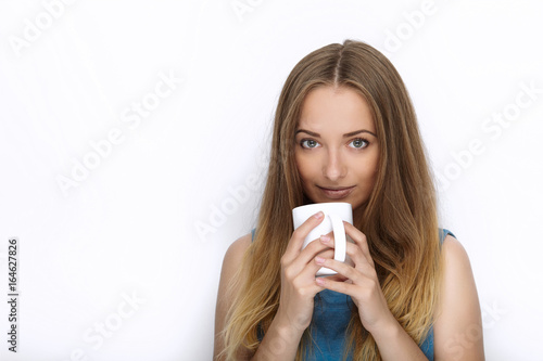 Headshot of young adorable playful blonde woman with cute smile in cobalt color blouse posing with big pure white mug on white backdrop