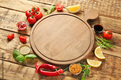 Wooden board, different sauces and vegetables on table
