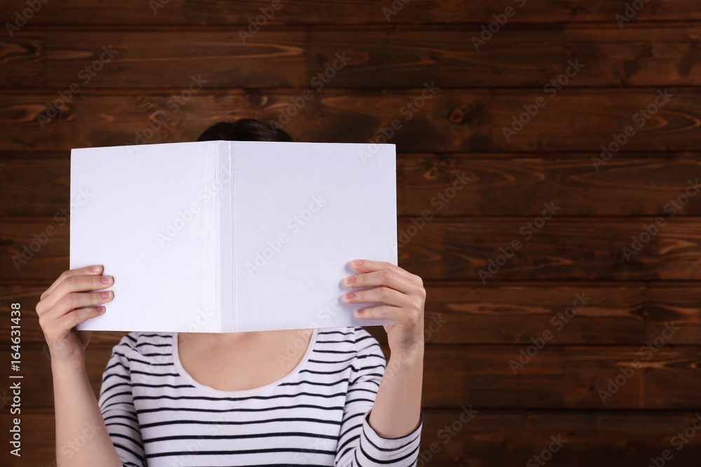 Woman holding open book with blank cover on wooden background Woman holding open book with blank cover on wooden background