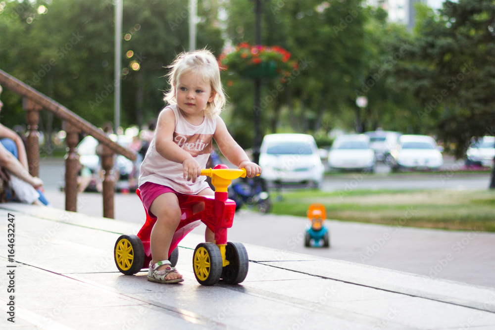 A little girl is riding a balance bike in the park. A little girl is riding a balance bike in the park.