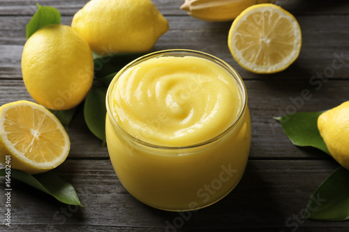 Beautiful composition with delicious lemon curd on wooden table photo