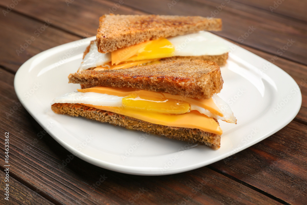 Delicious sandwiches with over easy egg and cheese on kitchen table