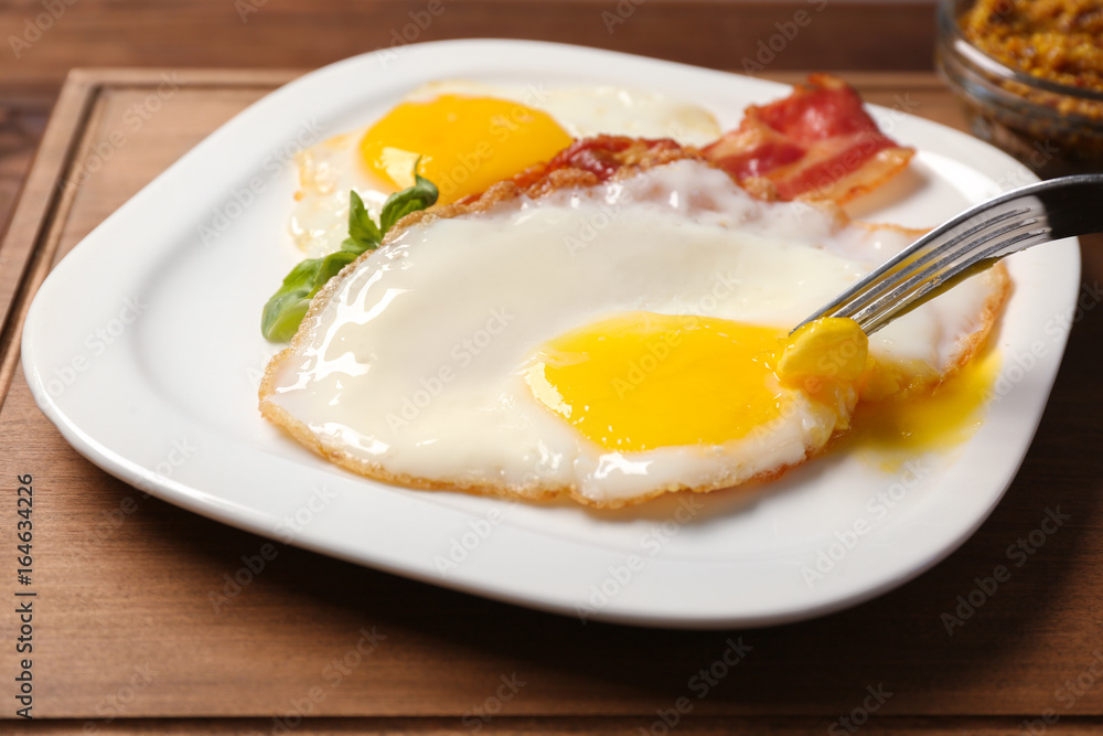 Eating delicious over easy eggs with bacon on kitchen table Eating delicious over easy eggs with bacon on kitchen table