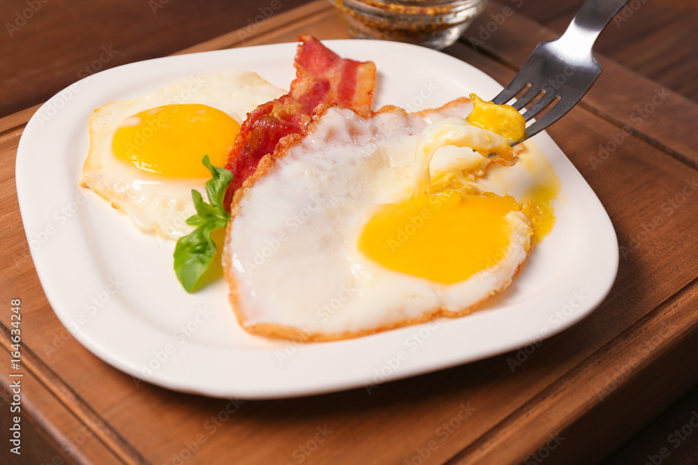 Eating delicious over easy eggs with bacon on kitchen table Eating delicious over easy eggs with bacon on kitchen table