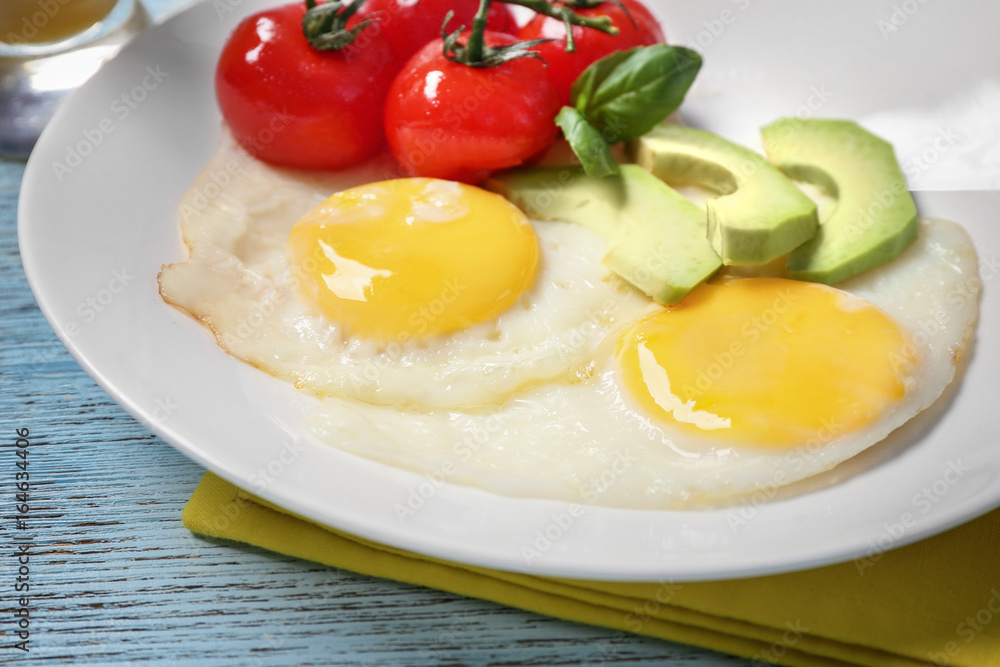 Delicious over easy eggs with avocado and tomatoes on kitchen table Delicious over easy eggs with avocado and tomatoes on kitchen table