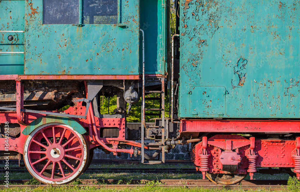 Naklejka premium Old retro steam locomotive wheels in summer. Vintage rustic green and red train standing on railways in Haapsalu, Estonia.