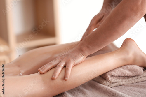 Young woman having legs massage in spa salon, closeup